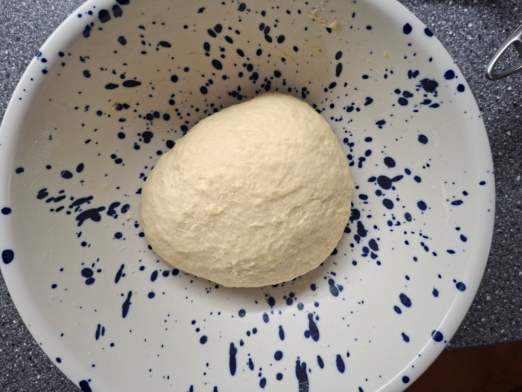 Bread dough in a white bowl with blue spots.